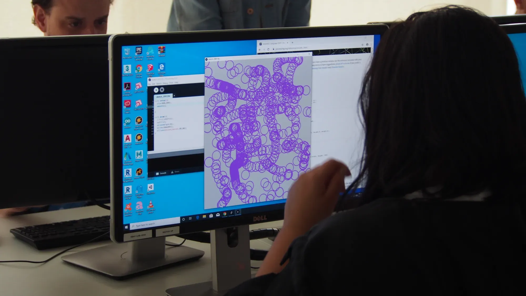 A participant viewing a purple generative drawing on a computer screen at PCD São Paulo